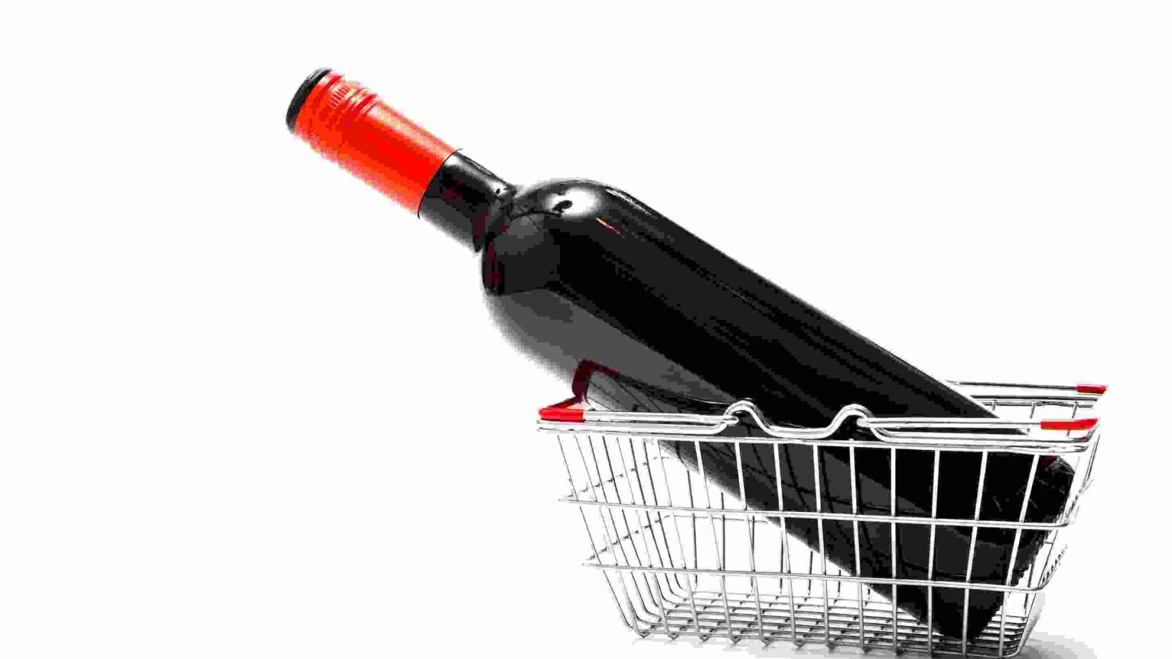 Miniature wire shopping basket with a bottle of red wine isolated on a white background with copy space